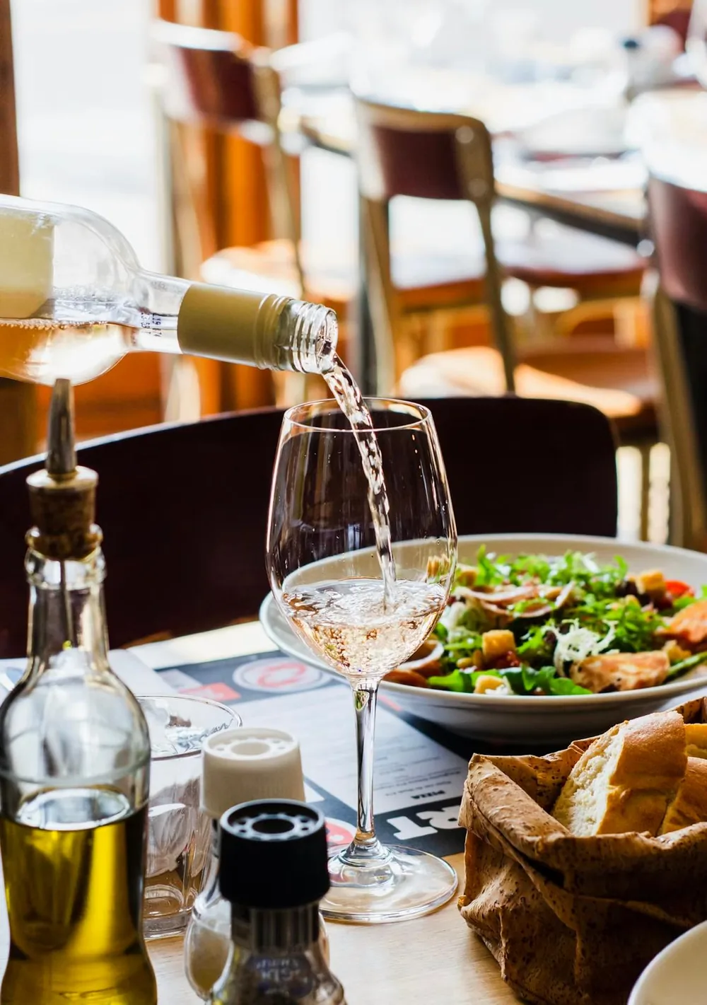 Točenje bijelog vina uz salatu i kruh u restoranu