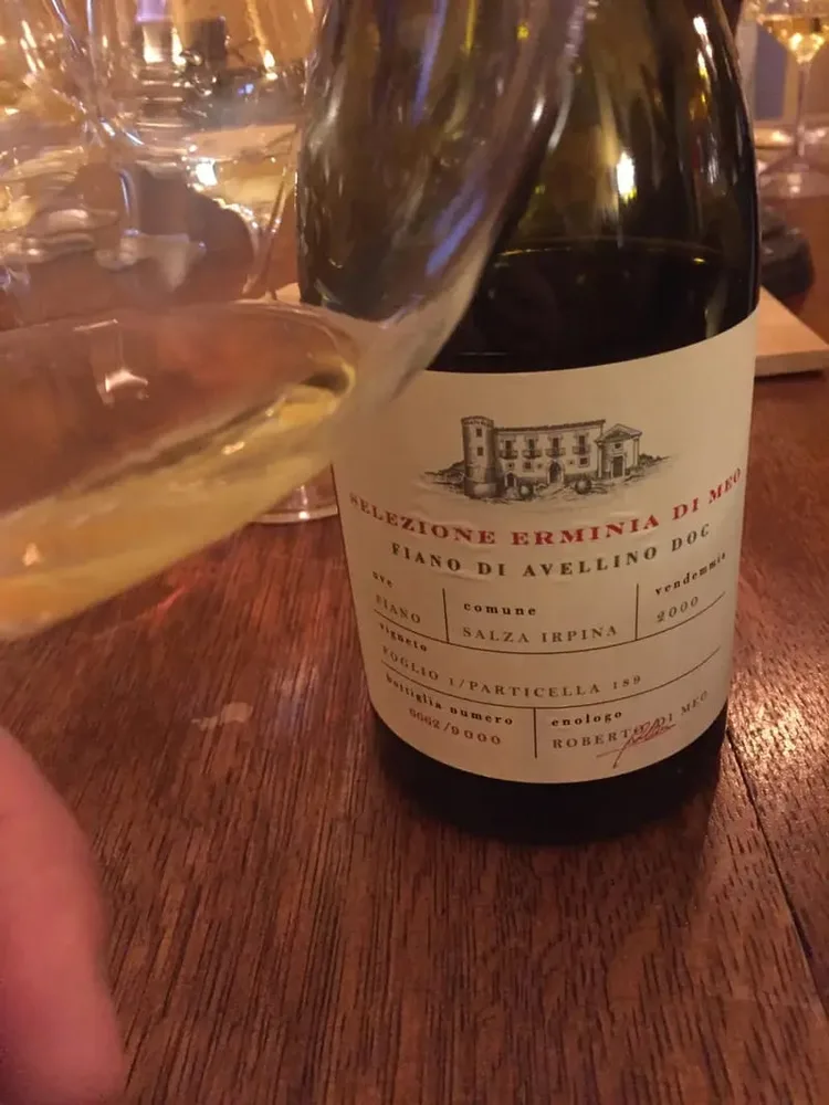 Čaša bijelog vina uz bocu na stolu