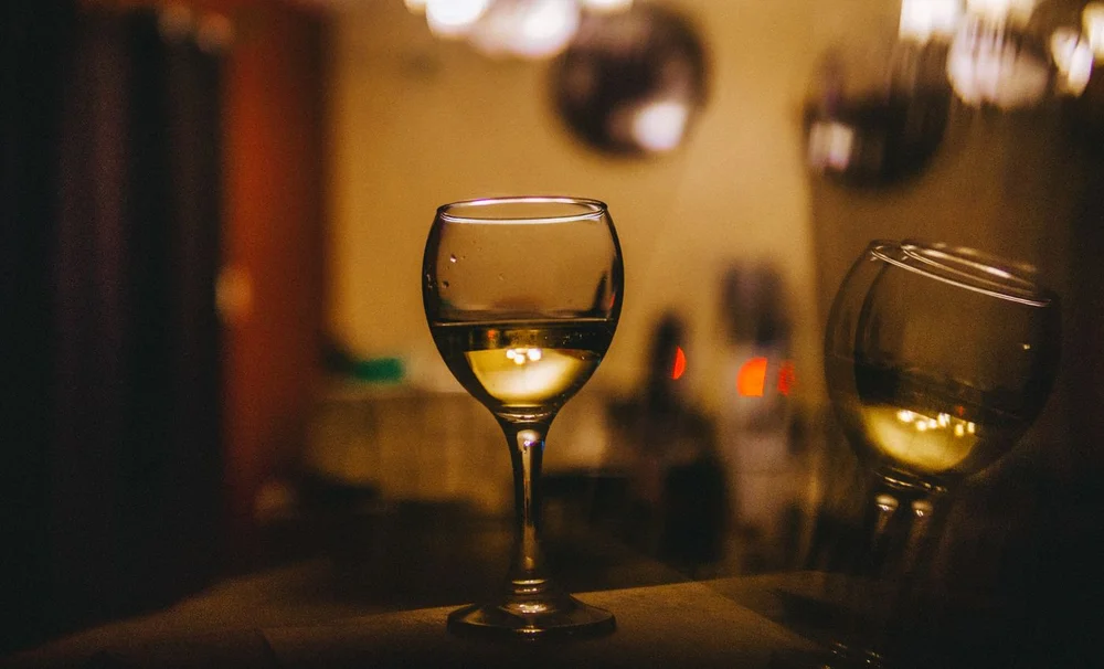 A glass of light white wine on a table in a warm setting