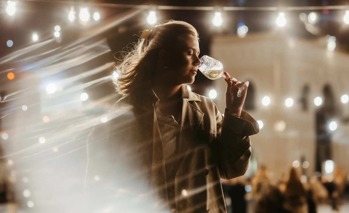 Posjetiteljica kuša vino pod festivalskim lampicama